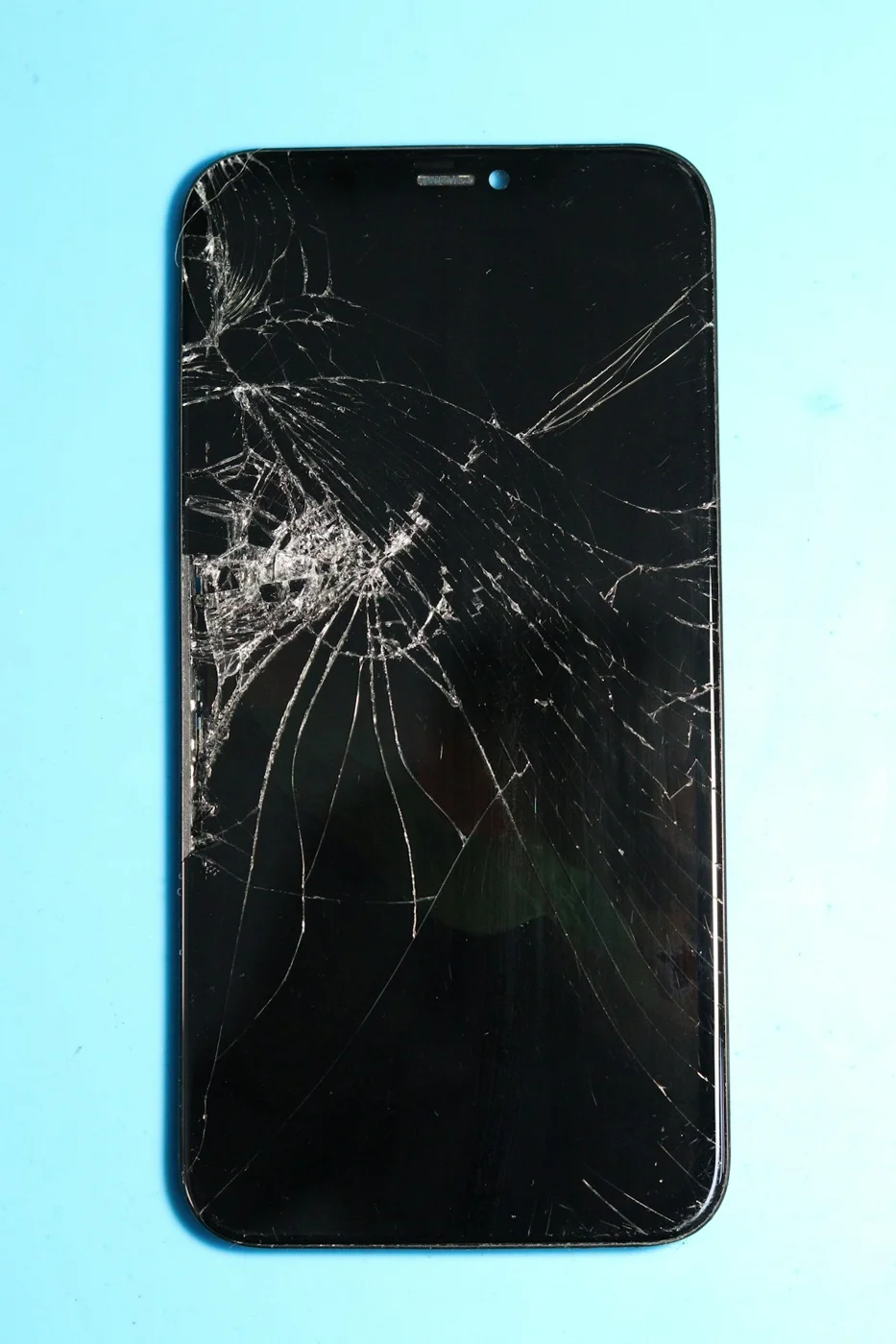 Close-up stock photograph of a mobile phone with heavily cracked screen glass