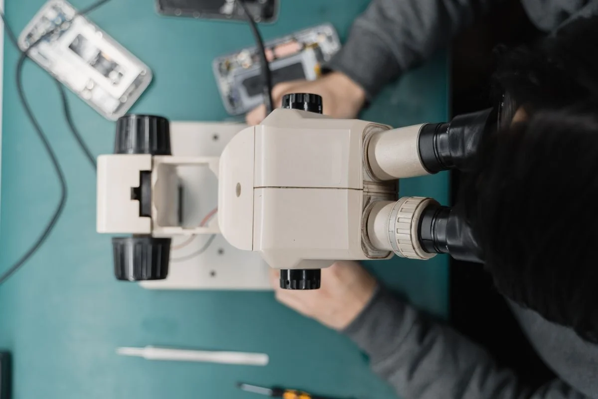 Overhead view of a repair microscope with opened mobile phones on a work mat
