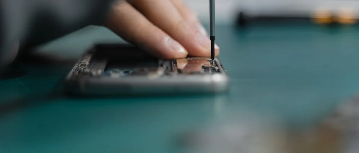 Hands using a precision screwdriver on an opened mobile phone
